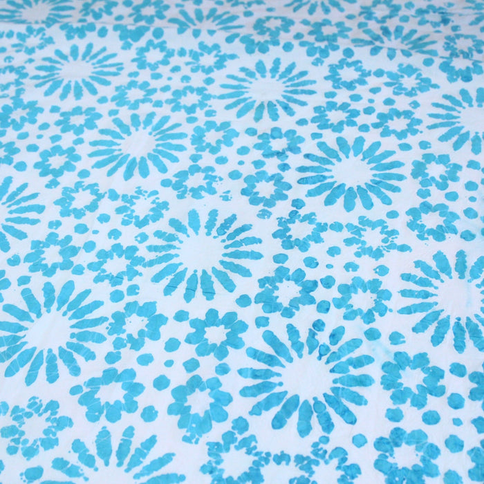 Tissu de coton batik gaufré aux fleurs et soleils bleu turquoise, fond bleu ciel - TissusPapi.com