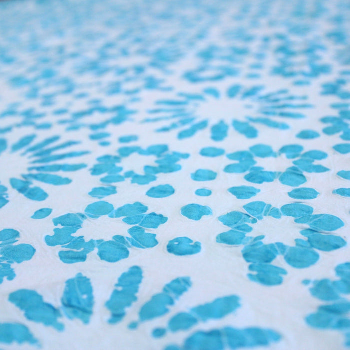 Tissu de coton batik gaufré aux fleurs et soleils bleu turquoise, fond bleu ciel - TissusPapi.com