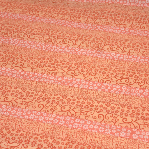 Tissu de coton batik patchwork aux fleurs variées, tons orange et pêche - TissusPapi.com