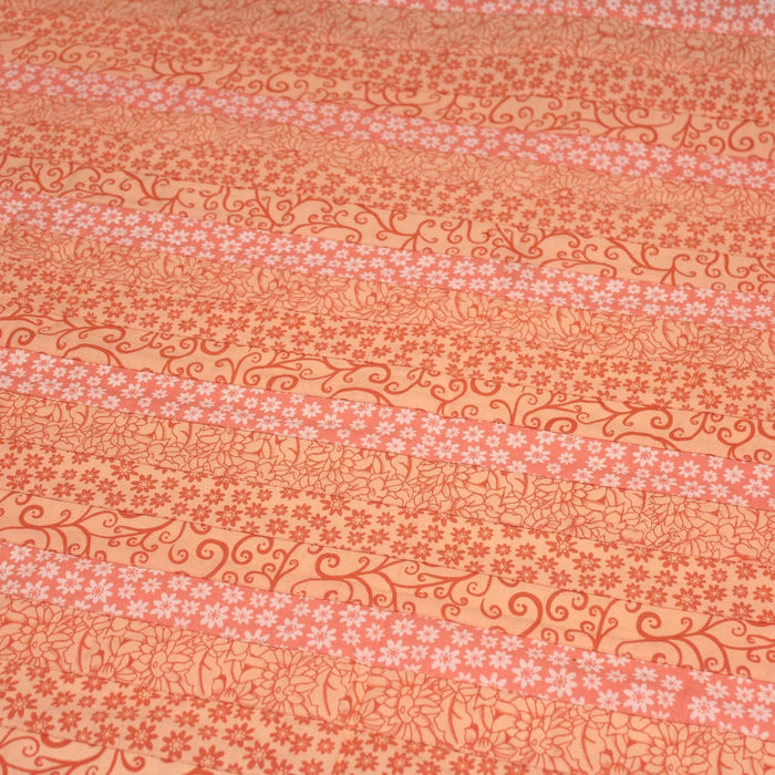 Tissu de coton batik patchwork aux fleurs variées, tons orange et pêche - TissusPapi.com