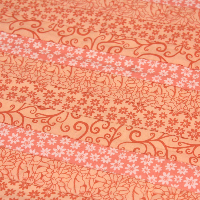 Tissu de coton batik patchwork aux fleurs variées, tons orange et pêche - TissusPapi.com