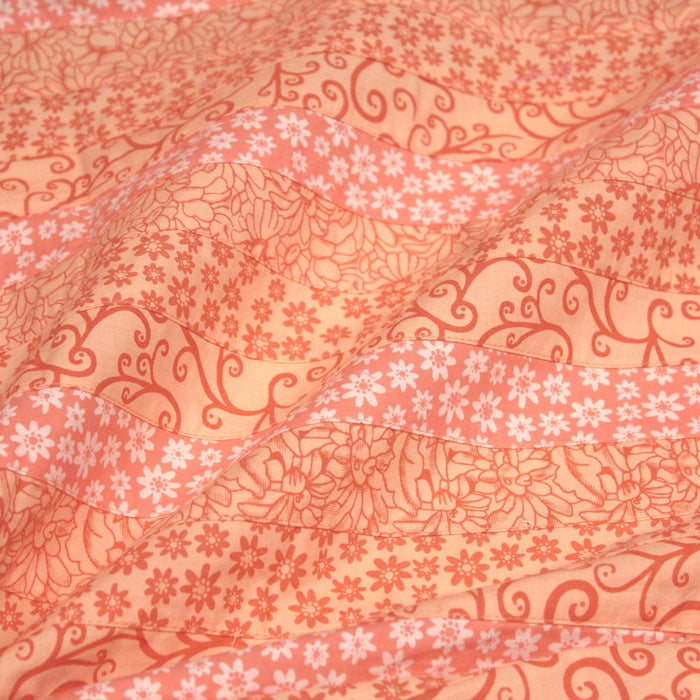 Tissu de coton batik patchwork aux fleurs variées, tons orange et pêche - TissusPapi.com