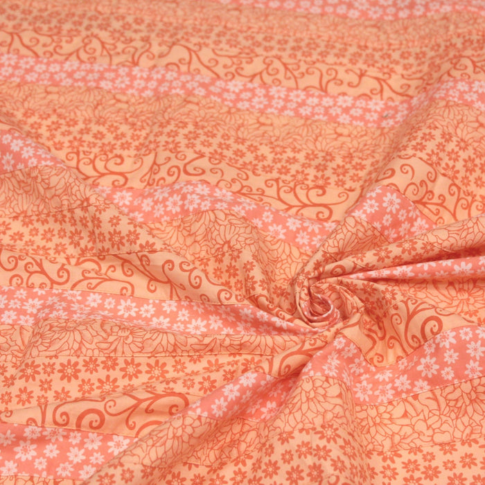 Tissu de coton batik patchwork aux fleurs variées, tons orange et pêche - TissusPapi.com