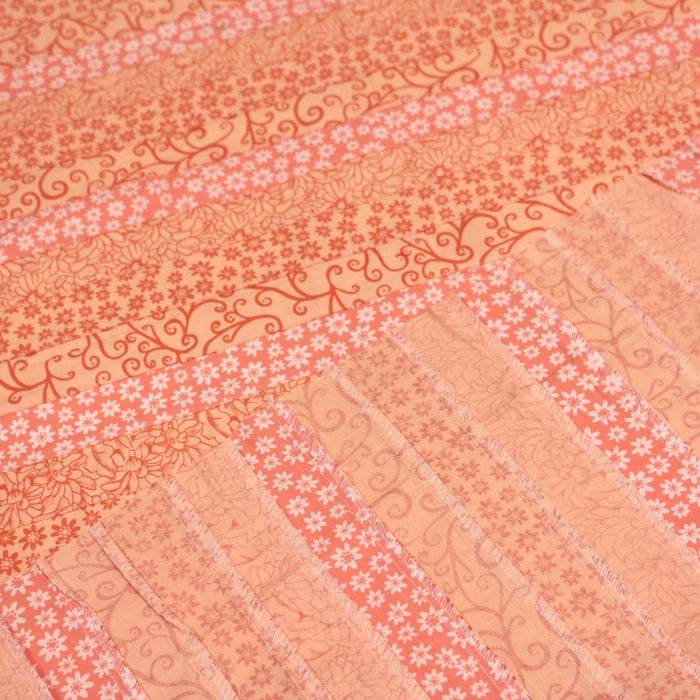 Tissu de coton batik patchwork aux fleurs variées, tons orange et pêche - TissusPapi.com