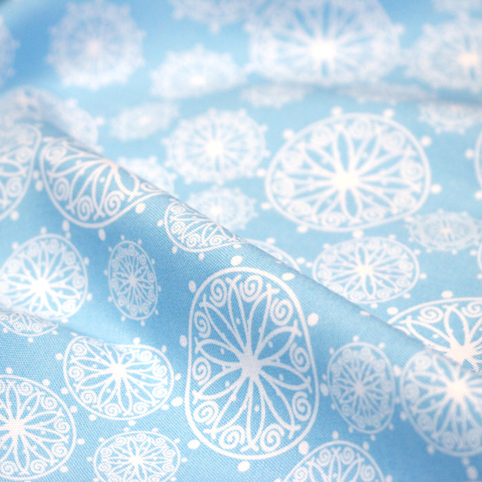 Tissu de Noël cotonnade bleu ciel aux rosaces blanches