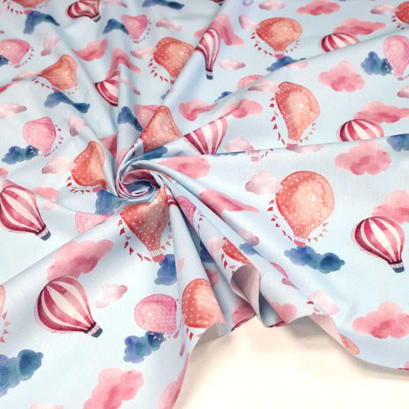 Tissu cotonnade enfant aux montgolfières roses et nuages sur fond bleu ciel