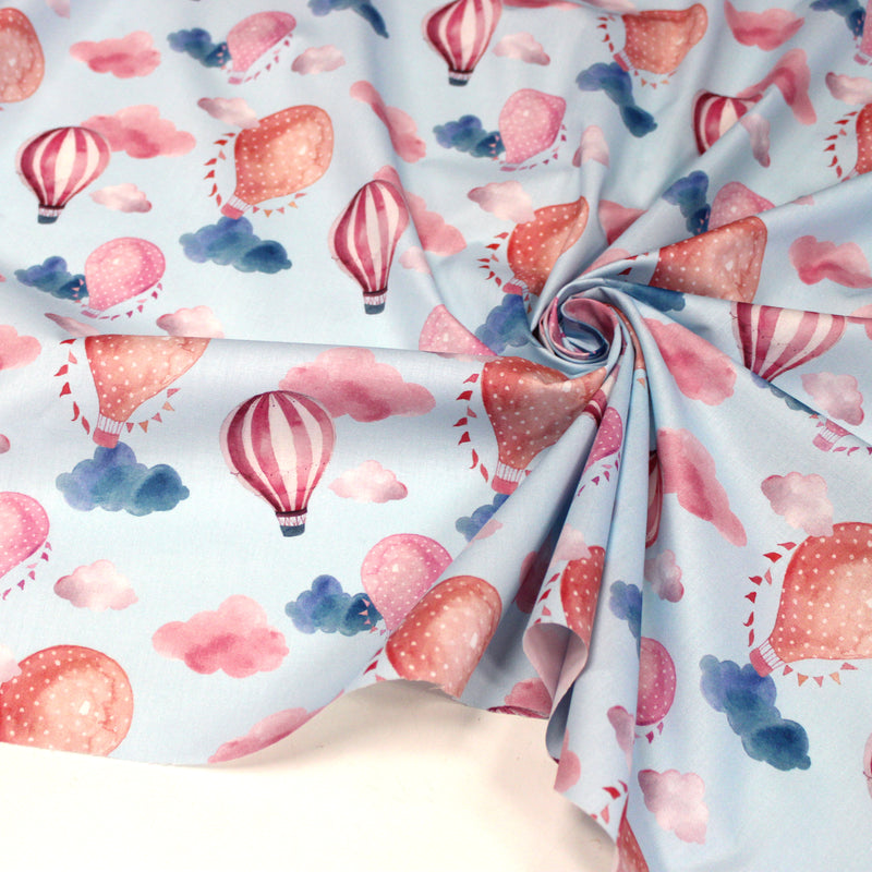 Tissu cotonnade enfant aux montgolfières roses et nuages sur fond bleu ciel