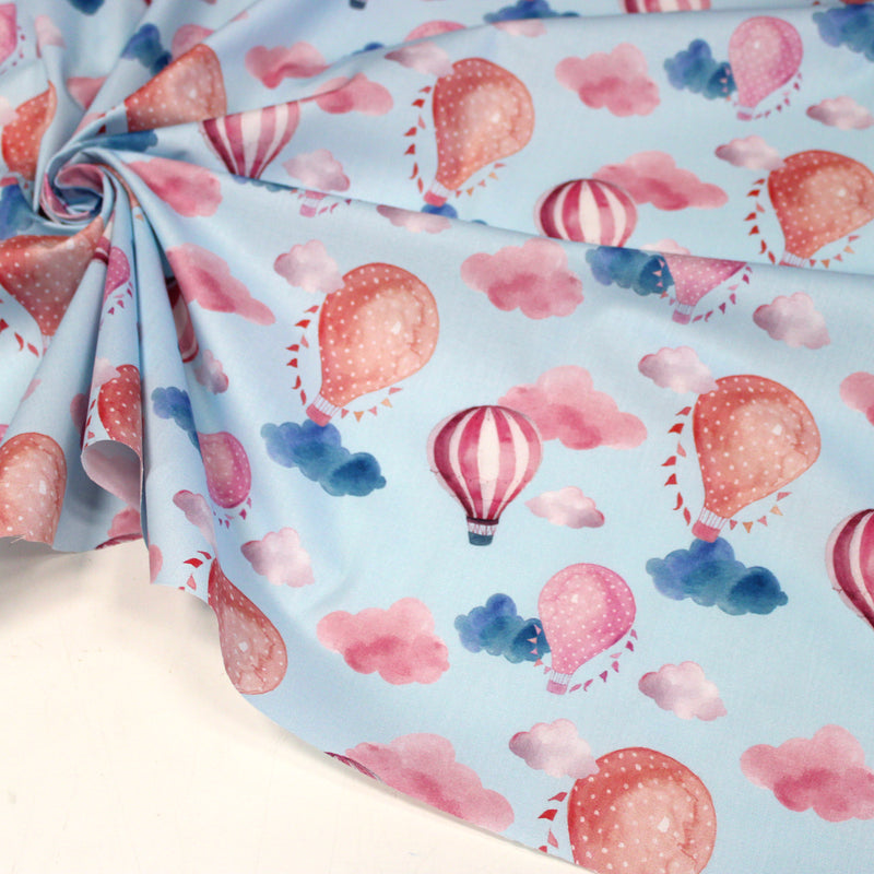 Tissu cotonnade enfant aux montgolfières roses et nuages sur fond bleu ciel