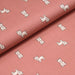 Tissu popeline de coton aux petits chiens écrus, fond vieux rose - tissuspapi