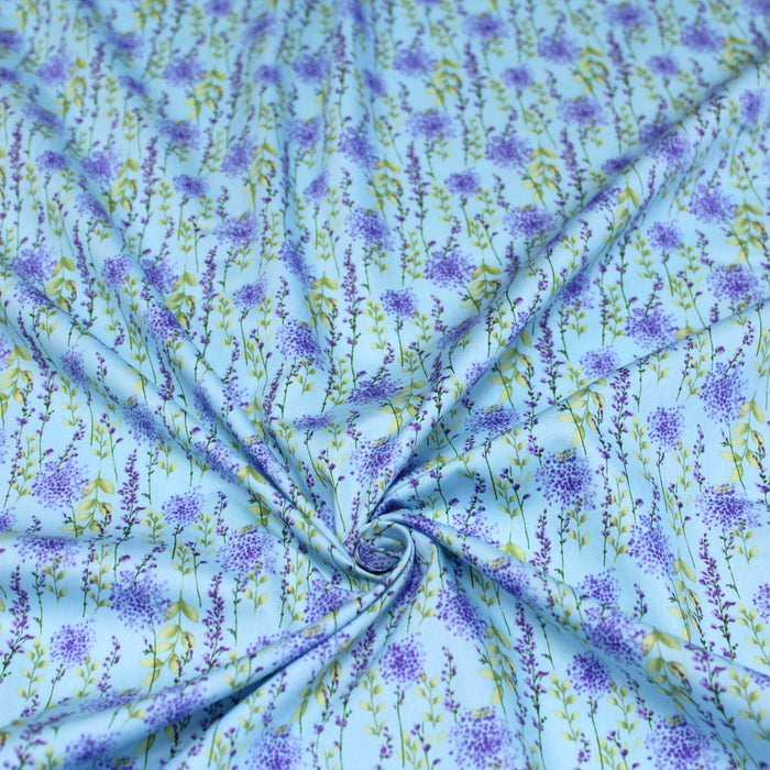 Tissu popeline de coton LAVANDE aux fleurs parme et feuilles vertes, fond bleu ciel