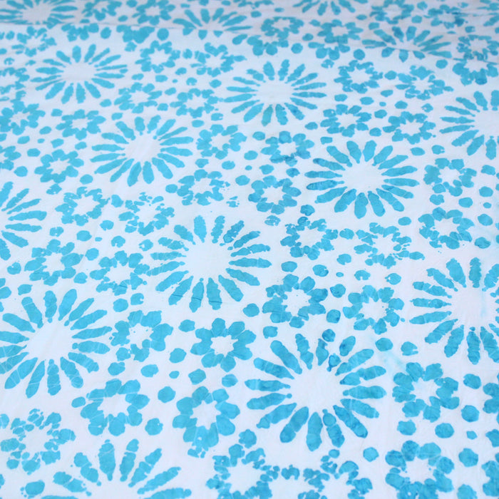 Tissu de coton batik gaufré aux fleurs et soleils bleu turquoise, fond bleu ciel
