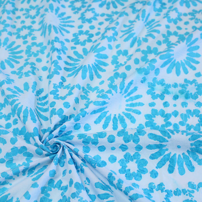 Tissu de coton batik gaufré aux fleurs et soleils bleu turquoise, fond bleu ciel