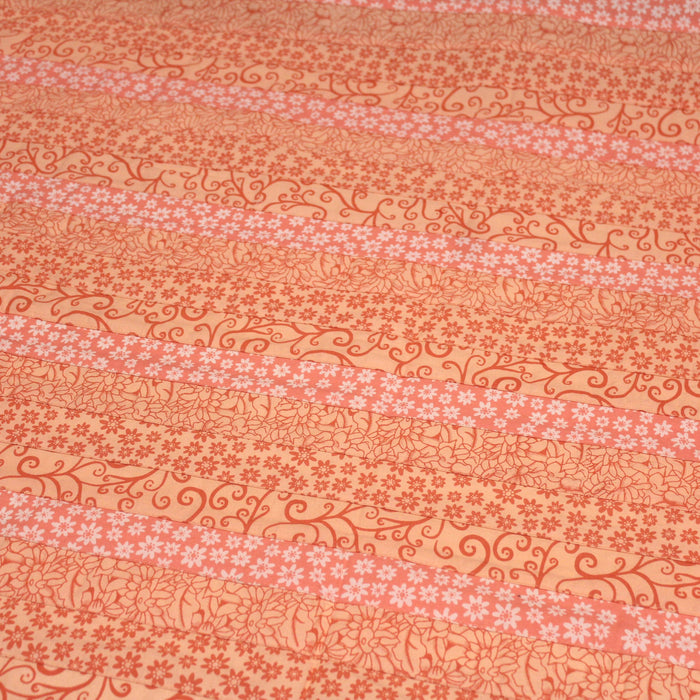 Tissu de coton batik patchwork aux fleurs variées, tons orange et pêche